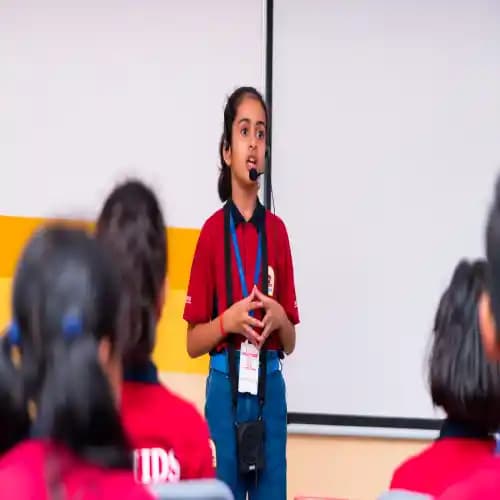 A young student confidently delivering a speech in a public speaking activity while wearing a headset microphone.